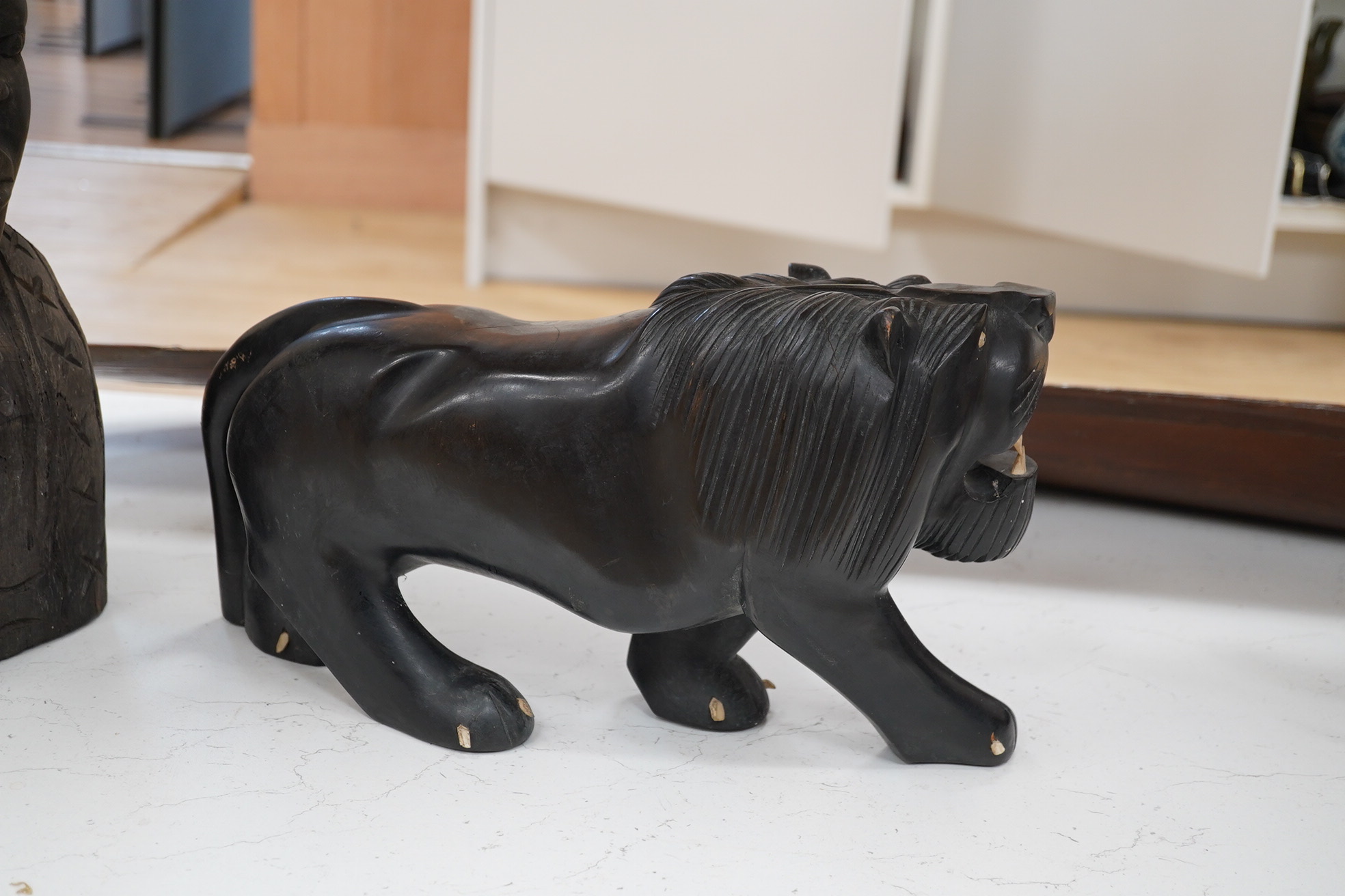 An African hardwood carving of a bust, 41cm high and an ebony Indian carving of a lion, 35cm long, (2). Condition - fair